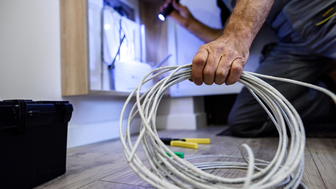 network installer holding white cables and shining torch on white router box